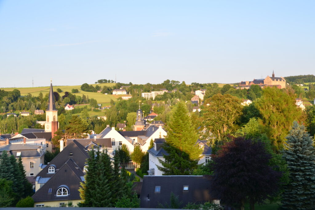 Blick über Stollberg mit Kirche und Häusern. Auf einem Hügel steht Schloss Hoheneck.